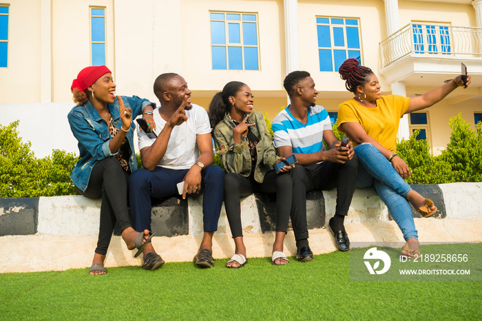 group african students sitting outside feeling excited about what they saw on their mobile phone.