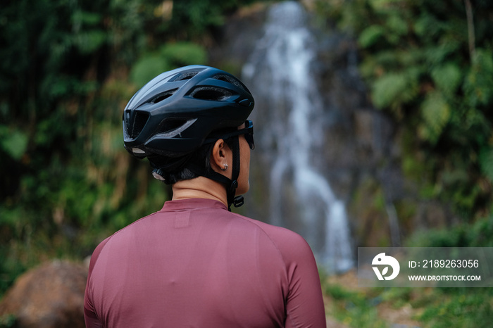 A young female cyclist is looking at the waterfalls.