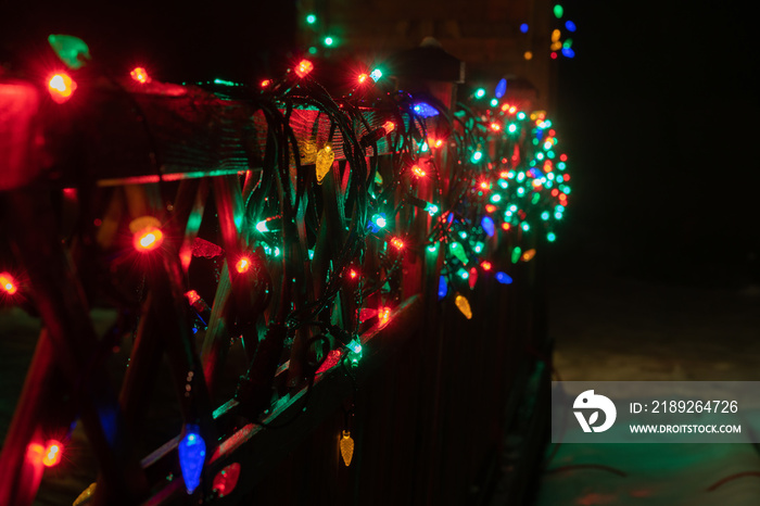 Real blurry Christmas Multicolored Lights on wooden terrace fence. Many flashing lamps that sequenti