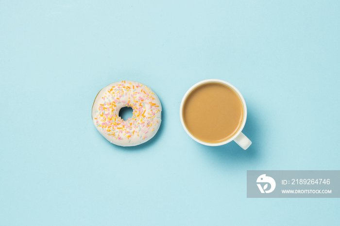 Fresh tasty sweet donut and a cup of coffee or tea with milk on a blue background. Fast food concept