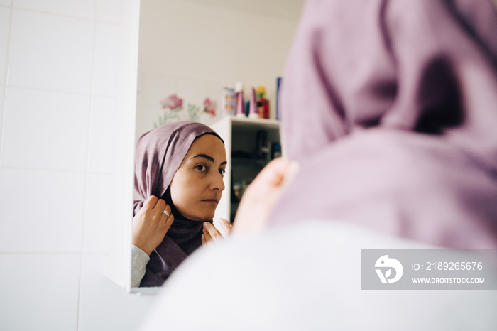 Close-up of mature woman wearing hijab while looking at mirror