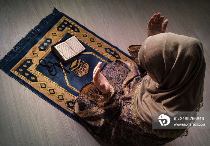 Muslim woman praying for Allah muslim god at room near window. Hands of muslim woman on the carpet p