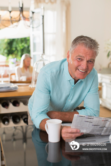 Portrait happy senior man reading newspaper and drinking coffee
