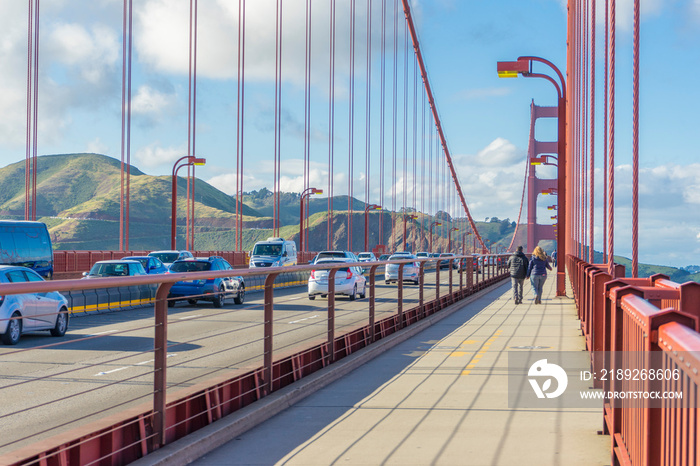 Many tourists walking up the Golden Gate Bridge against blue sky in San Francisco, CA