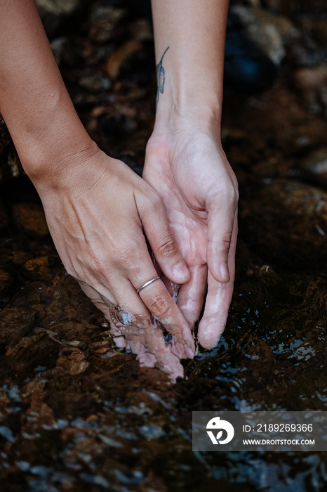 A young female cyclist is washing her hands by the creek