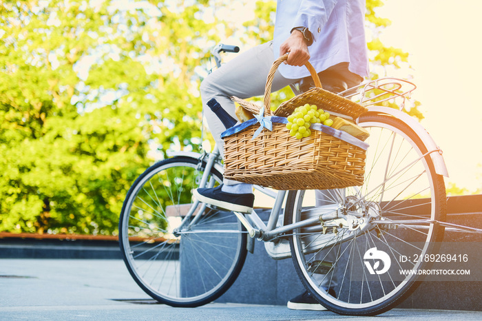 A man on a city bicycle holds picnic basket.