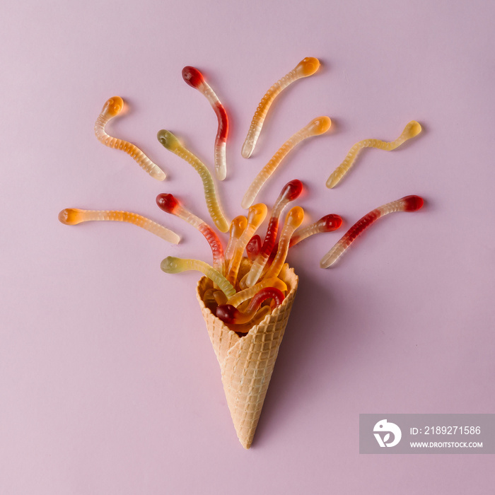 Ice cream cone with gummy candy on pastel pink background. Minimal food concept. Flat lay.