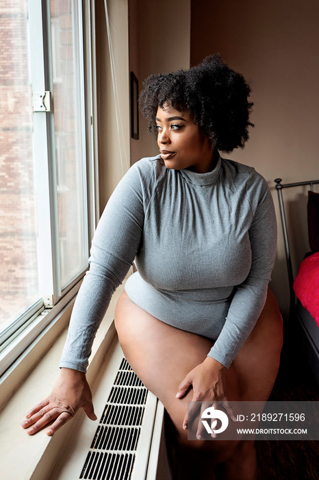 Plus size Black Woman sitting in front of a window