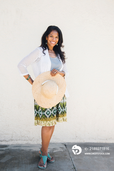 Portrait of senior woman, outdoors, holding sun hat, smiling