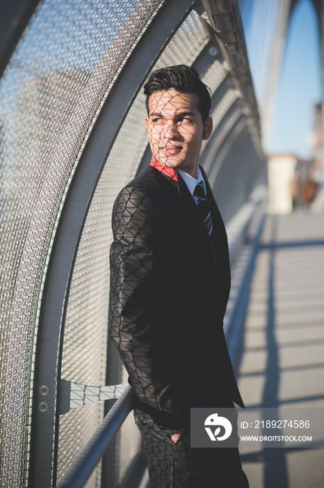 Young businessman by bridge safety fence