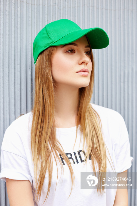 灰色墙壁背景上戴着绿色帽子的美丽金发女孩