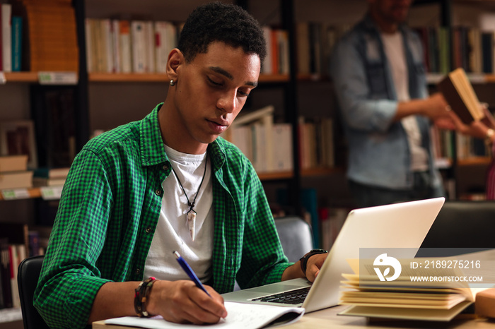 Young male student study in the library using laptop for researching online.