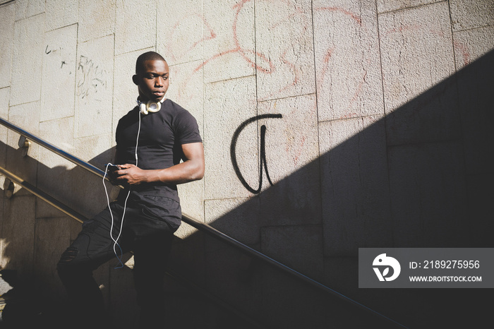 Portrait of young man outdoors, leaning against railing, looking away