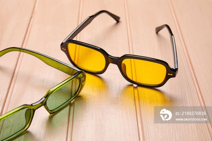 Different modern sunglasses on color wooden background, closeup