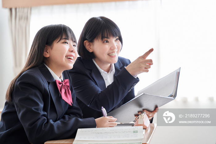 教室で先生に教えてもらう日本人女子中学生