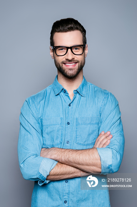 Portrait of happy fashionable handsome man in jeans shirt and glasses crossing hands and smiling