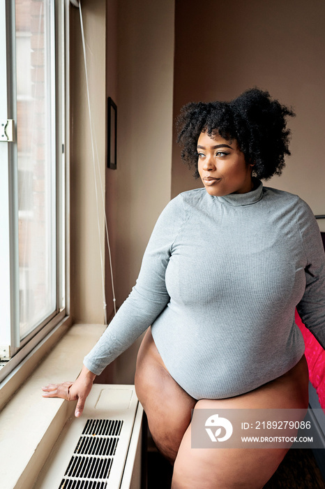 Plus size Black Woman standing in front of a window