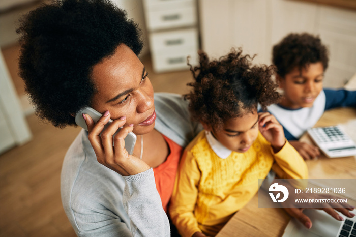 Black single mother talking on the phone while working at home.