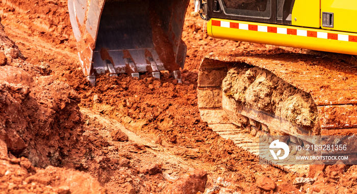 Backhoe working by digging soil at construction site. Bucket of backhoe digging soil. Crawler excava