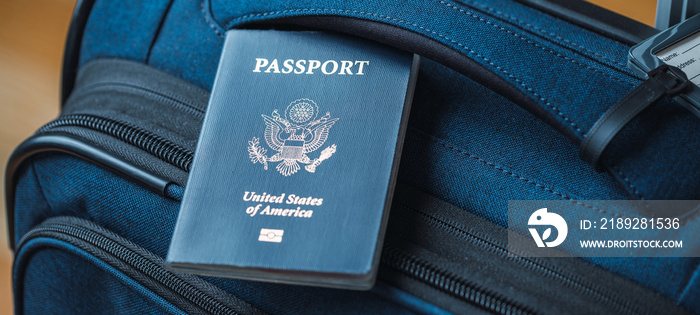 A blue American passport sitting on top of a blue suitcase