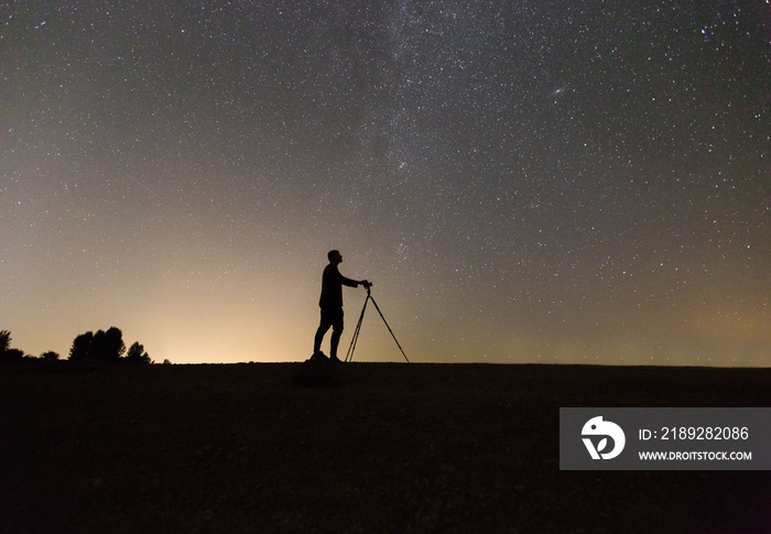 silhouette of photographer shooting night stars