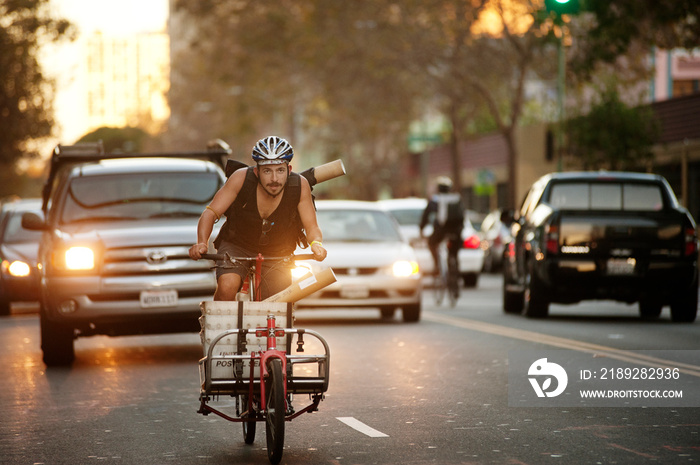 Male athlete cycling on street during sunset