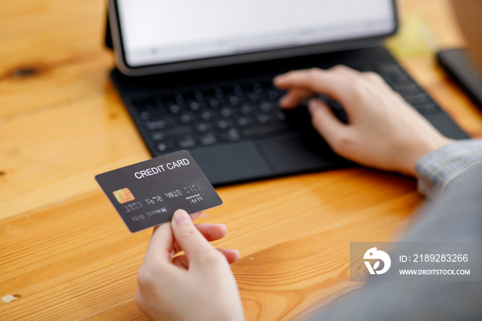 女性手持信用卡，使用智能手机和平板电脑进行网上购物的特写