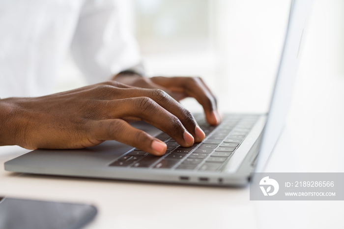 Close up of african business man hands working using keyboard of computer laptop