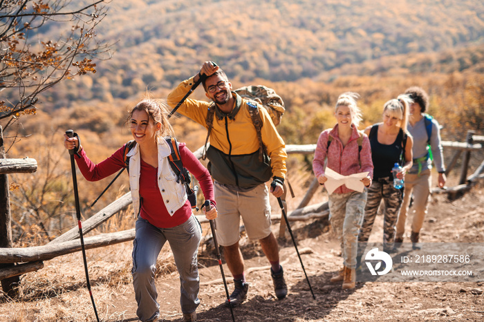 Small happy group of people hiking in the autumn while walking in the row.