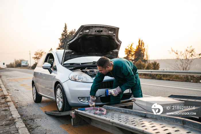 拖车服务中的道路助理工人试图用起动机和能量计启动汽车发动机