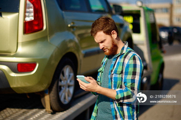 Man calling while tow truck picking up car