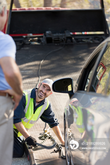 Smiling male roadside assistance mechanic preparing to tow car