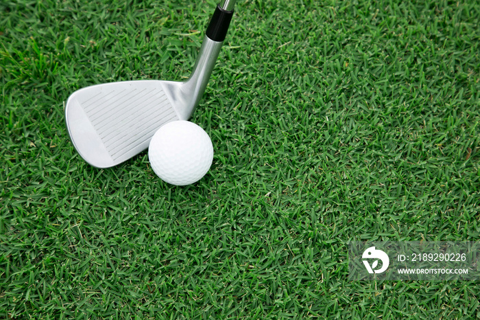 Top view of iron golf club and golf ball on the green grass