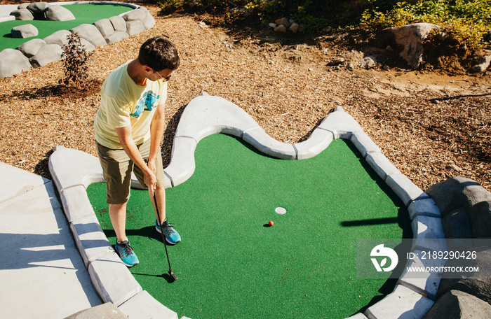 High angle view of mid adult man playing golf at miniature golf course during summer