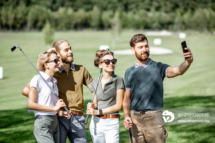 Group of young and happy friends making selfie photo while standing together with golf putters durin