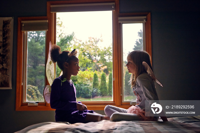 Friends in Halloween costumes sitting on bed