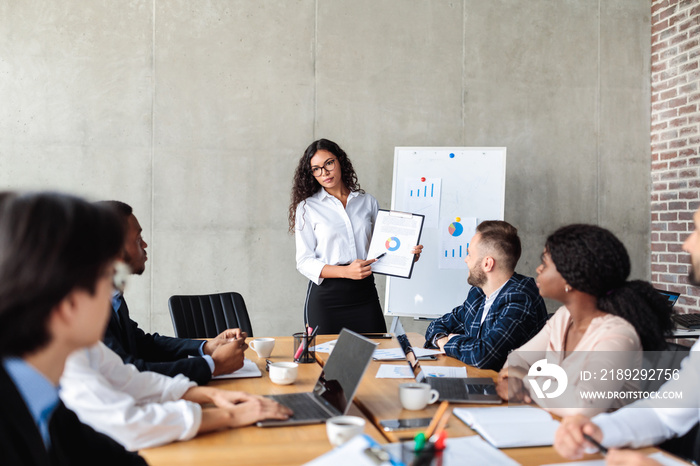 Female Marketing Specialist Making Business Presentation For Coworkers In Office