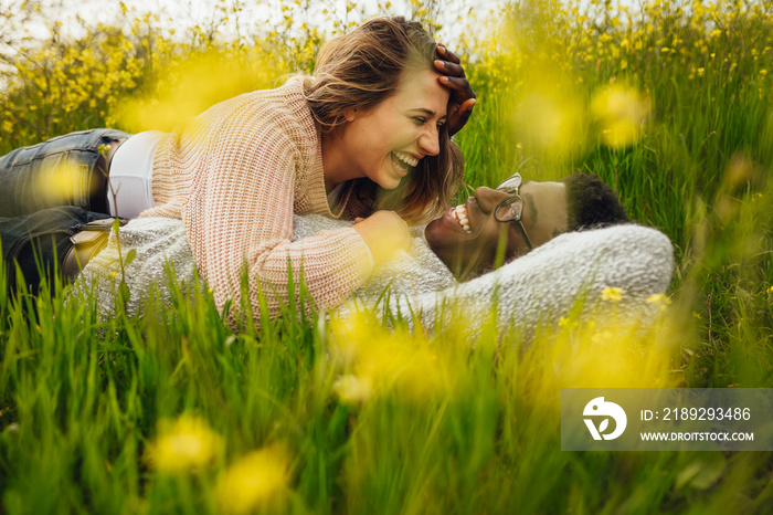 Interracial couple lying on grass and laughing