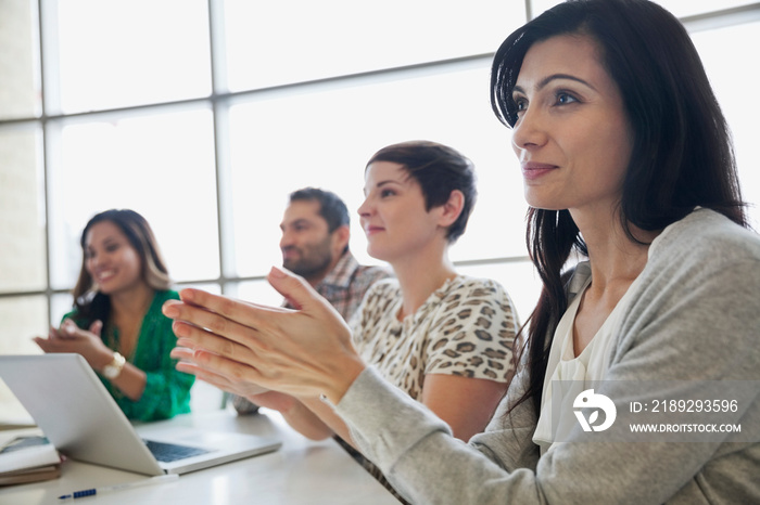 Business people applauding around conference table