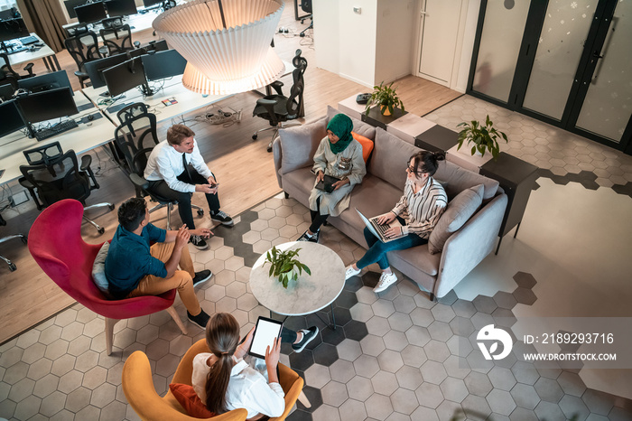 Top view photo of Multiethnic startup business team having brainstorming in relaxation area of moder