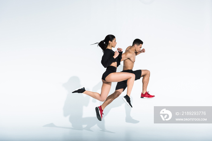 side view of sportive multicultural woman and man in sportswear and sneaker running on white backgro