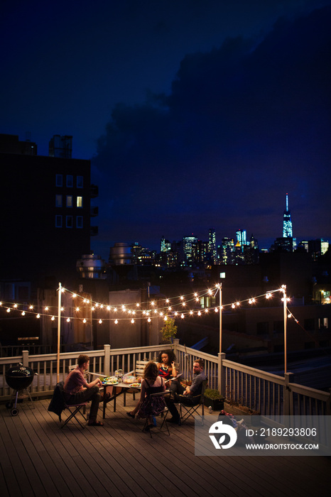 Group of friends sitting on roof terrace at night