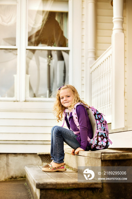 Portrait of cute girl (6-7) sitting on doorstep