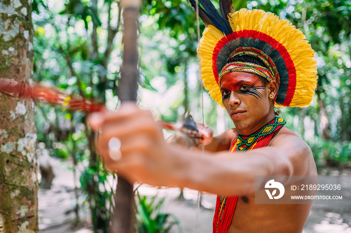 Indian from the Pataxó tribe using a bow and arrow. Brazilian Indian with feather headdress and neck