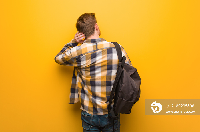 Young redhead student man from behind thinking about something