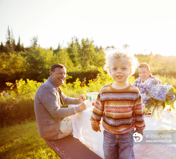 Portrait of girl (2-3) standing on bench at dining table outdoors