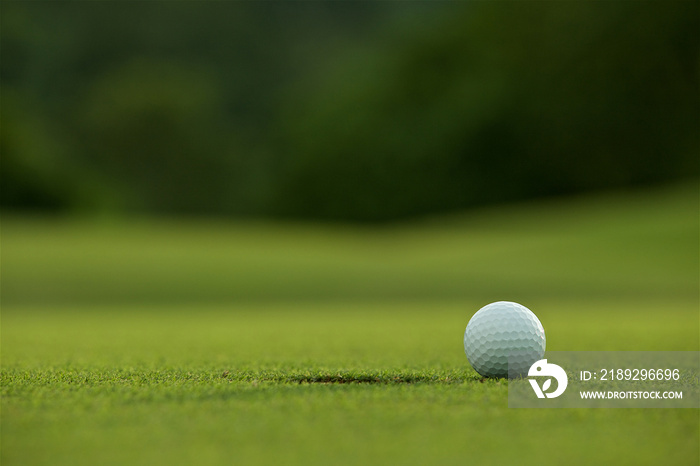 white golf ball near hole on fairway with the green background i