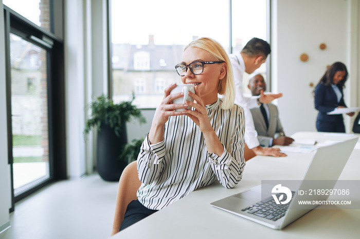 Smiling businesswoman drinking a coffee while working in an office