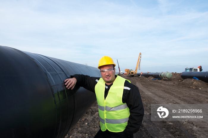 一名油田工人站在施工现场的煤气管道旁的肖像。