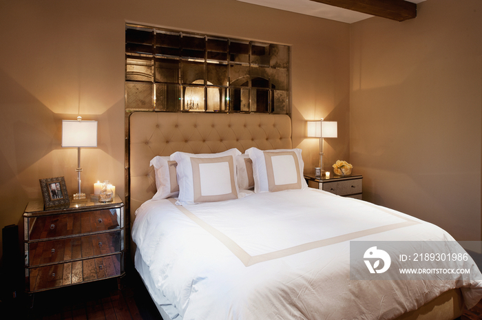 Lit lamps on side tables by cozy and tidy bed in bedroom at home; Rancho Sante Fe; USA